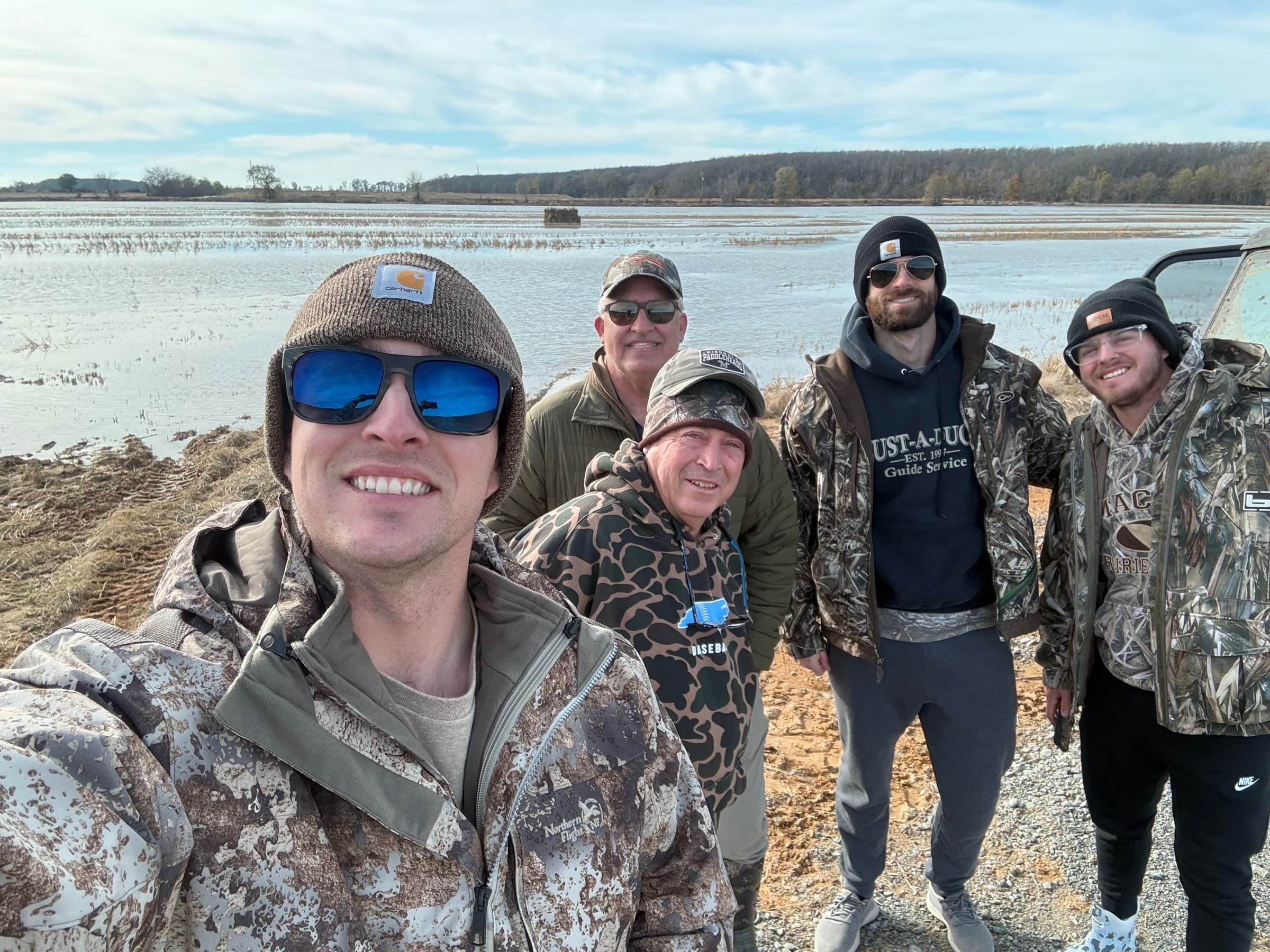 Family and friends dressed for a hunt beside flooded fields