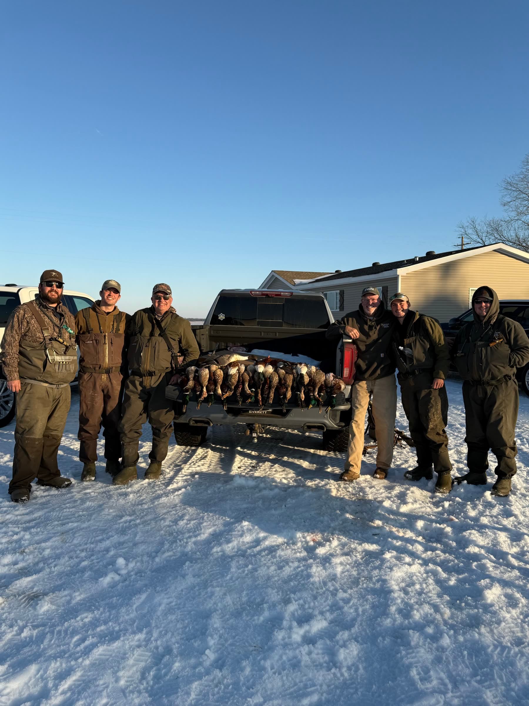 A group of hunters gathered beside a truck after a winter waterfowl hunt