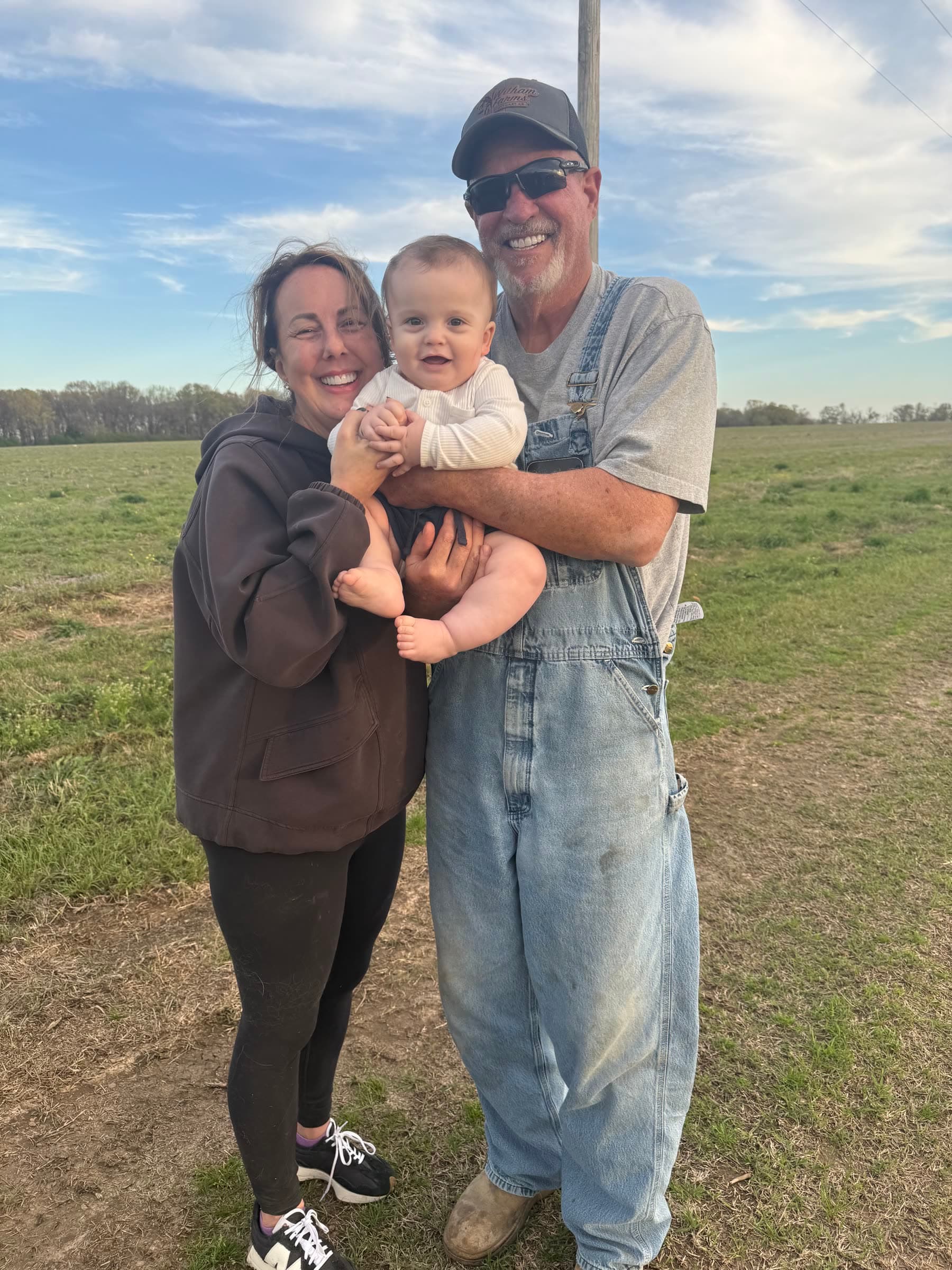 Witham family members holding a young child in a field