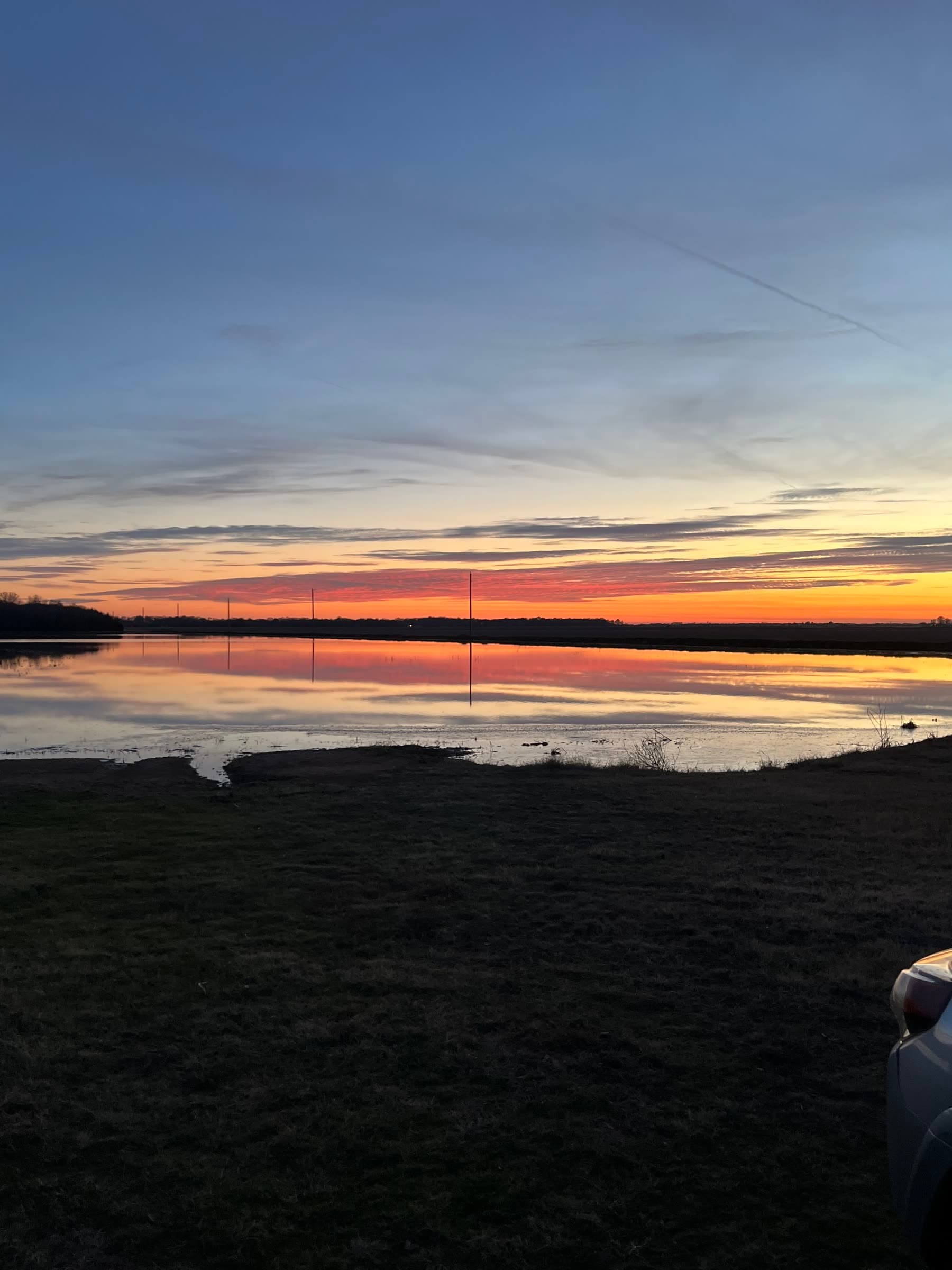 A pink and orange sunset reflected across calm water